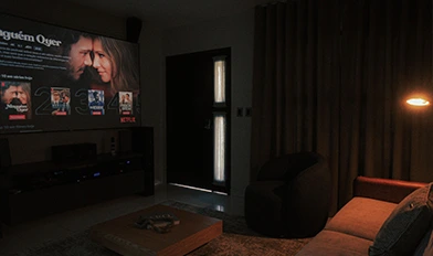 Sala de home cinema com iluminação automatizada e sistema audiovisual integrado